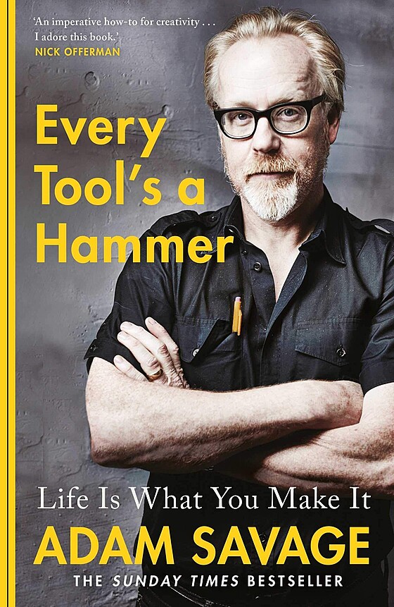 Book cover of "every tool's a hammer" by adam savage. features savage in glasses and a black shirt, looking directly at the camera, with arms crossed. background and text in yellow and black.