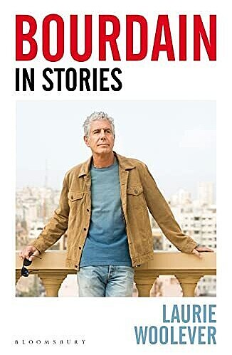 The cover of the book "Bourdain in Stories" by Laurie Woolever. The cover features a man in a tan jacket and blue shirt standing against a balcony with a cityscape in the background. The author's name is displayed at the bottom.