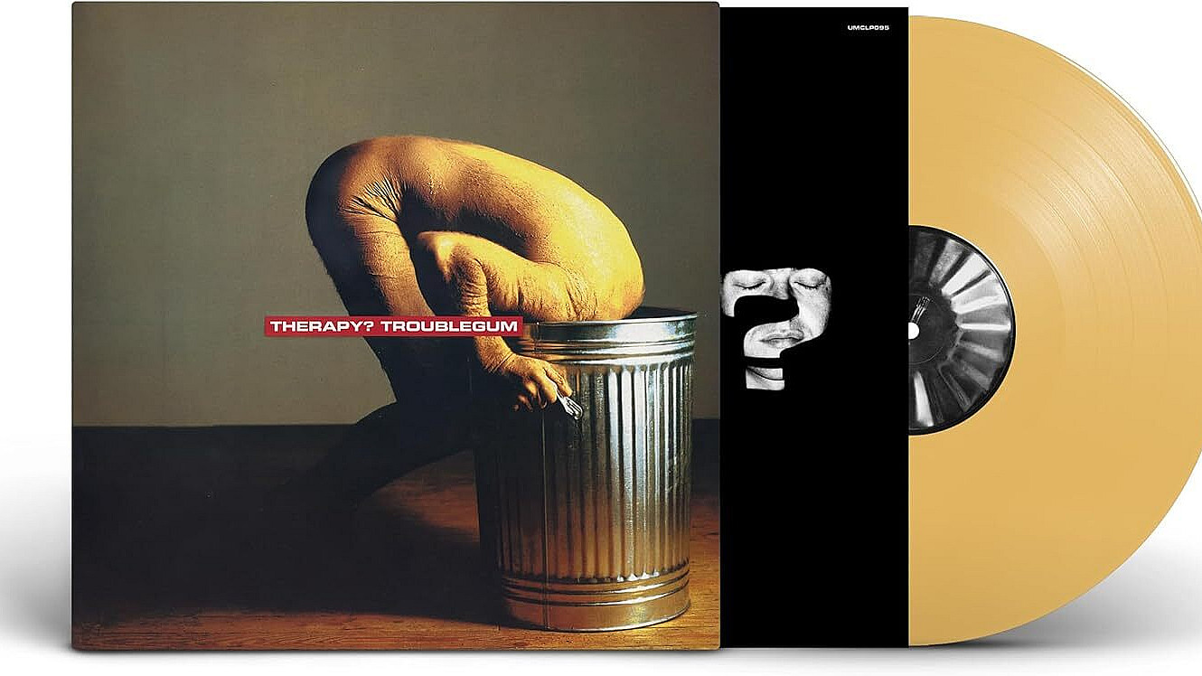 Album cover for "Troublegum" by Therapy?. It depicts a person with a shaved head and bare torso, crouching and bent forward with their head inside a large metal trash can, set against a plain background. The band and album name are in red text at the center.
