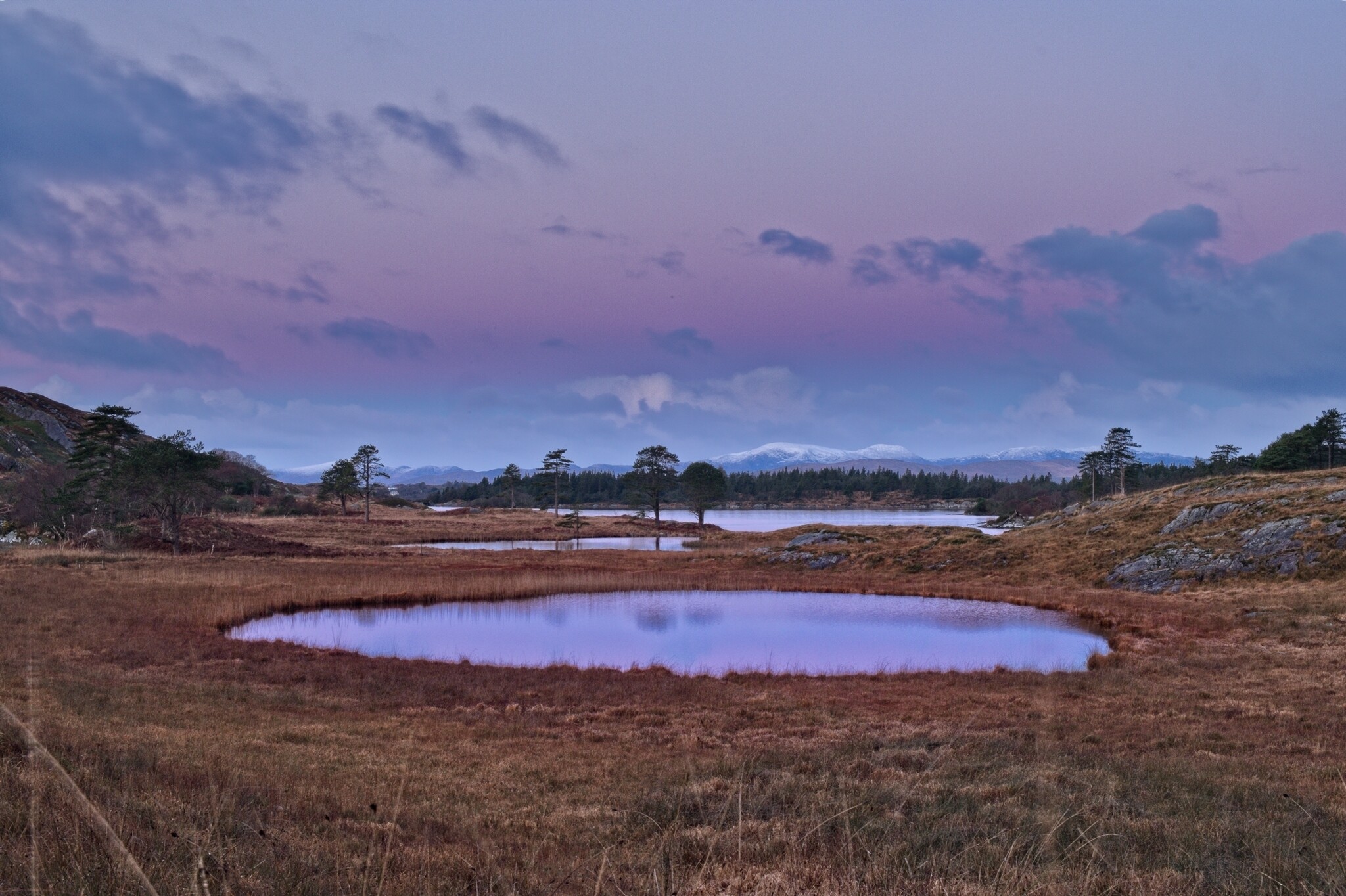 A beautiful sunset over a calm lake, with vibrant orange and pink colors reflecting on the water's surface.