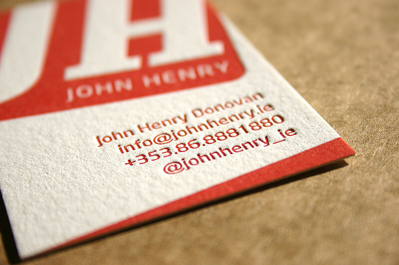 A business card displaying the contact information for John Henry Donovan. The card includes his email info@johnhenry.ie, phone number +353 86 888 1880, and social media handle @johnhenry_ie. The card is printed in red and white.