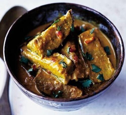 A bowl of aubergine curry, featuring large chunks of augbergine in a rich, golden sauce garnished with fresh cilantro, presented in a dark bowl against a light background.